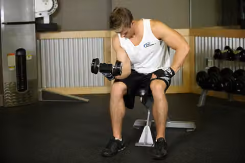 Demonstrasi gerakan Seated One-Arm Dumbbell Palms-Up Wrist Curl.