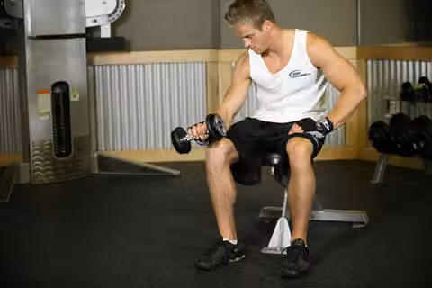 Demonstrasi gerakan Seated One-Arm Dumbbell Palms-Down Wrist Curl.
