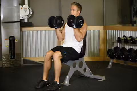 Demonstrasi gerakan Seated Dumbbell Curl.